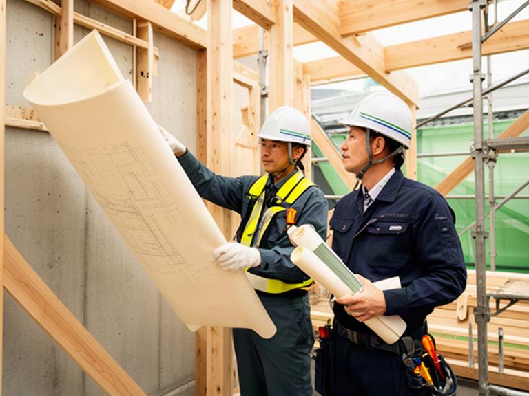 建築現場で図面を確認する設計者と施工担当者