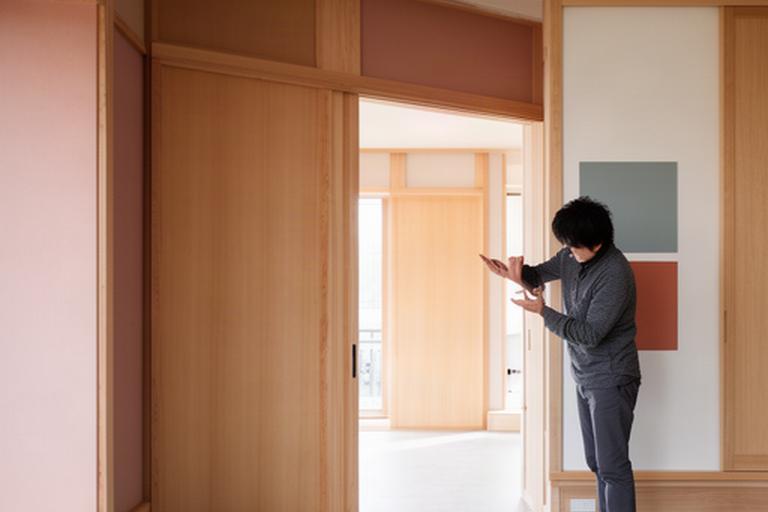 完成間近の室内で木製建具と壁の色味を確認する建築士